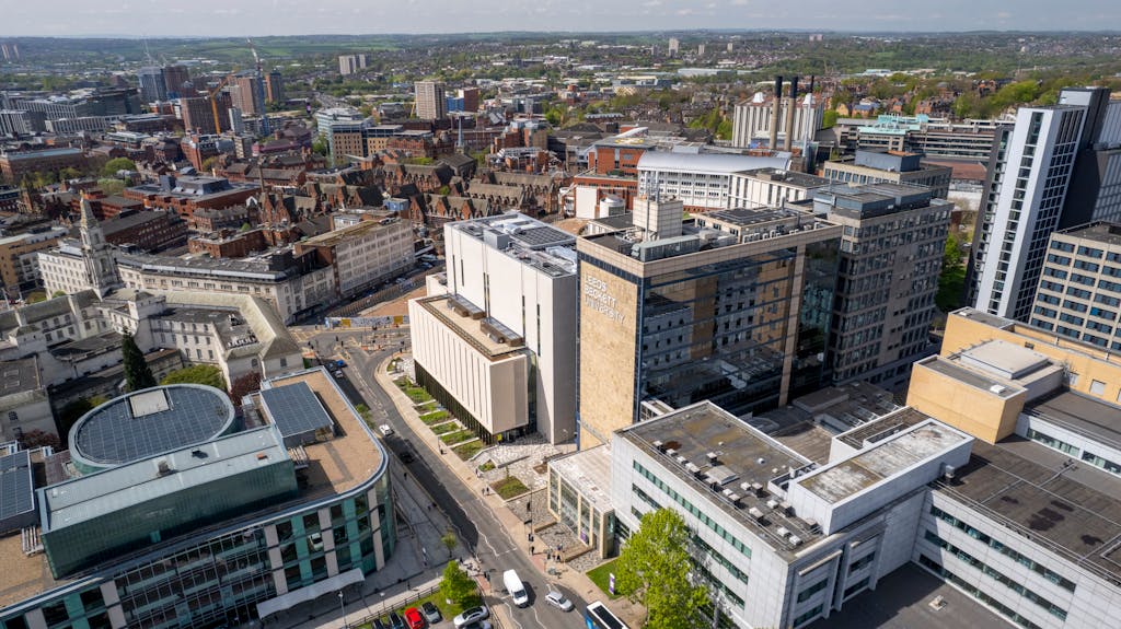 High-angle aerial view of Leeds cityscape showcasing modern and classic architecture, with Leeds Beckett University in focus.