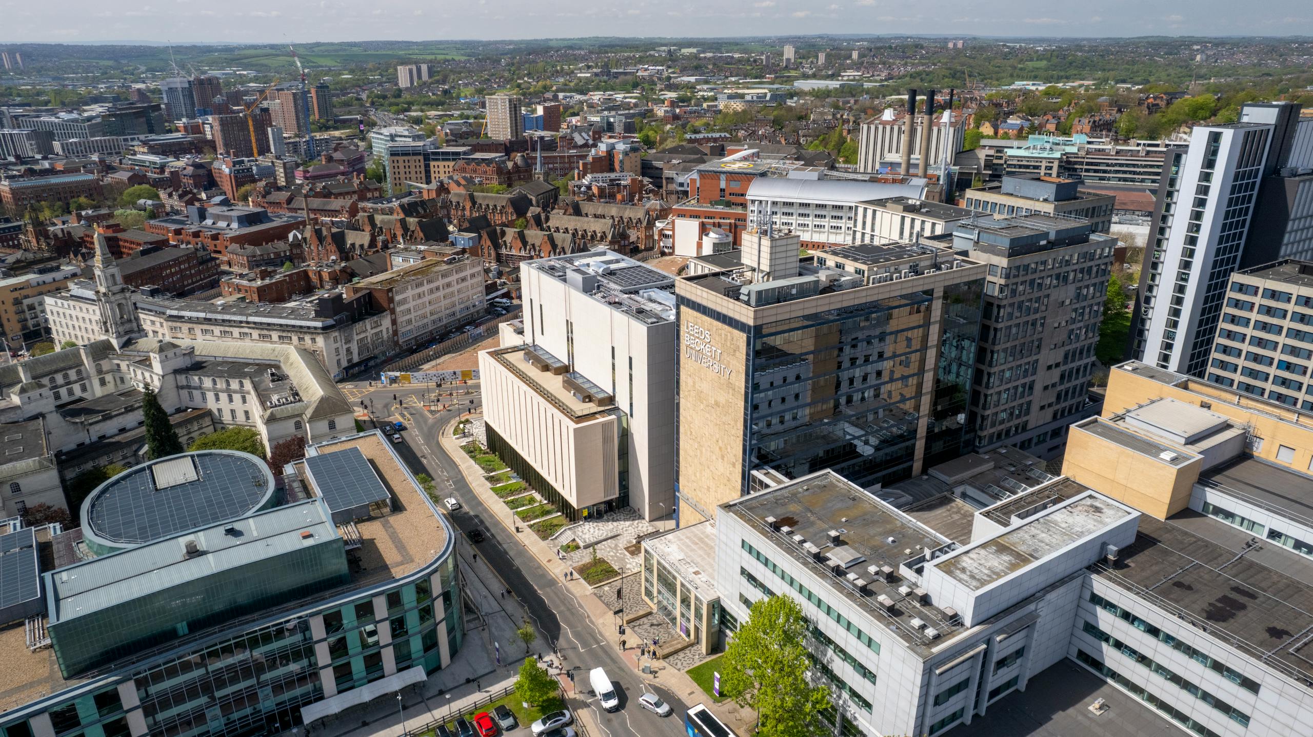 High-angle aerial view of Leeds cityscape showcasing modern and classic architecture, with Leeds Beckett University in focus.